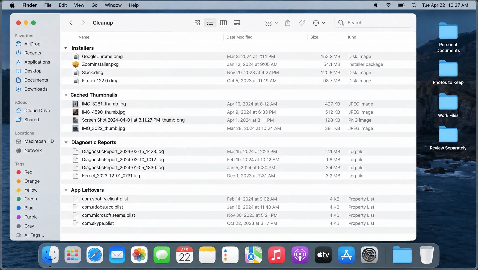 Overhead view of a Mac screen listing downloaded installers, cached thumbnails, old diagnostic reports, and app leftovers, with personal documents set aside for separate review.